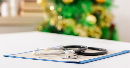 A stethoscope on a paper and folder, with a Christmas tree in the background